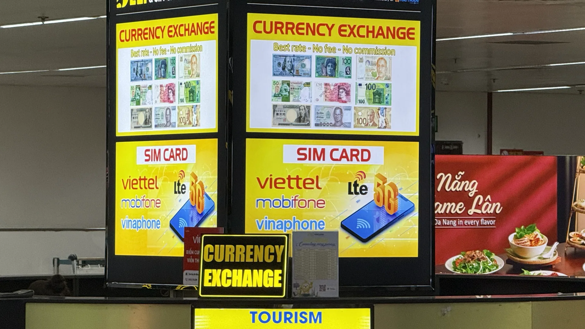 A combined currency exchange and SIM card counter in the arrivals hall at Da Nang airport, with signs offering Viettel, MobiFone and Vinaphone SIM cards on LTE and 5G
