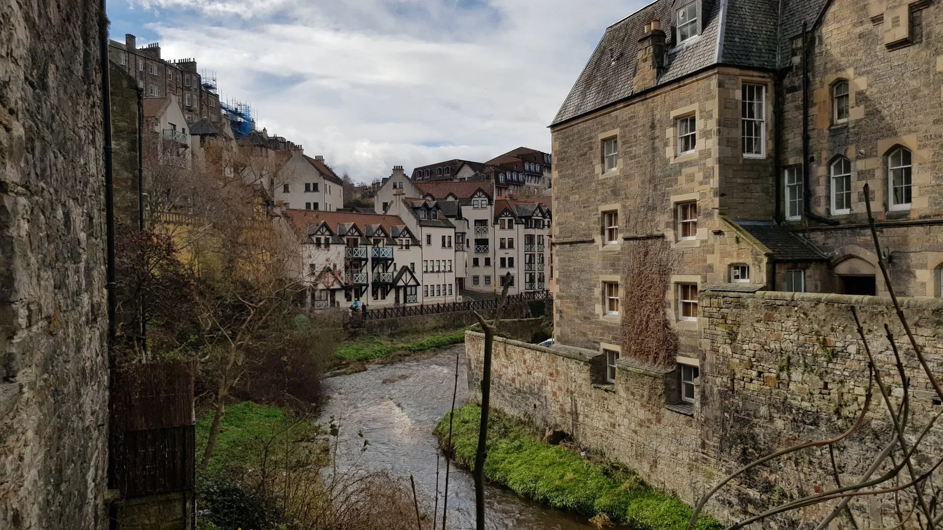 Historic stone houses along the Water of Leith in Dean Village, Edinburgh, with the city rising behind them