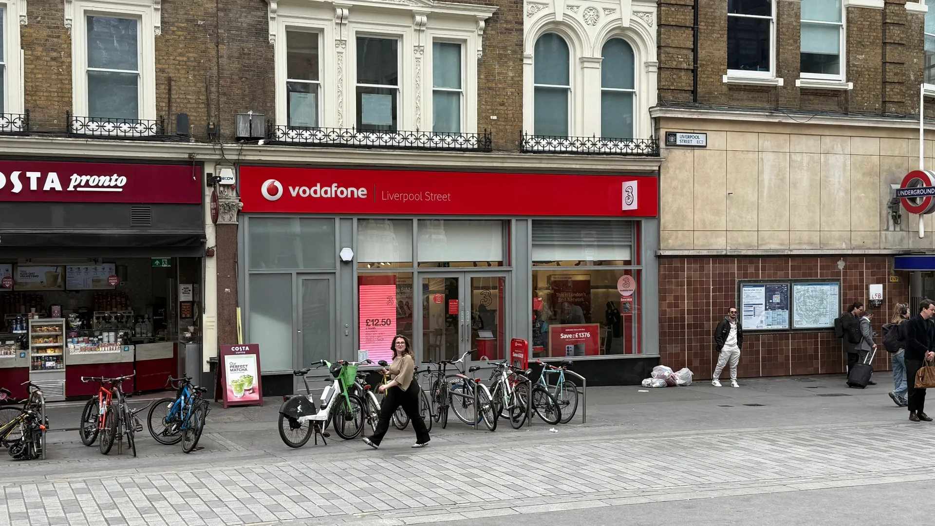 Vodafone shop on Liverpool Street in London with the Three logo on the same shopfront, next to an Underground entrance