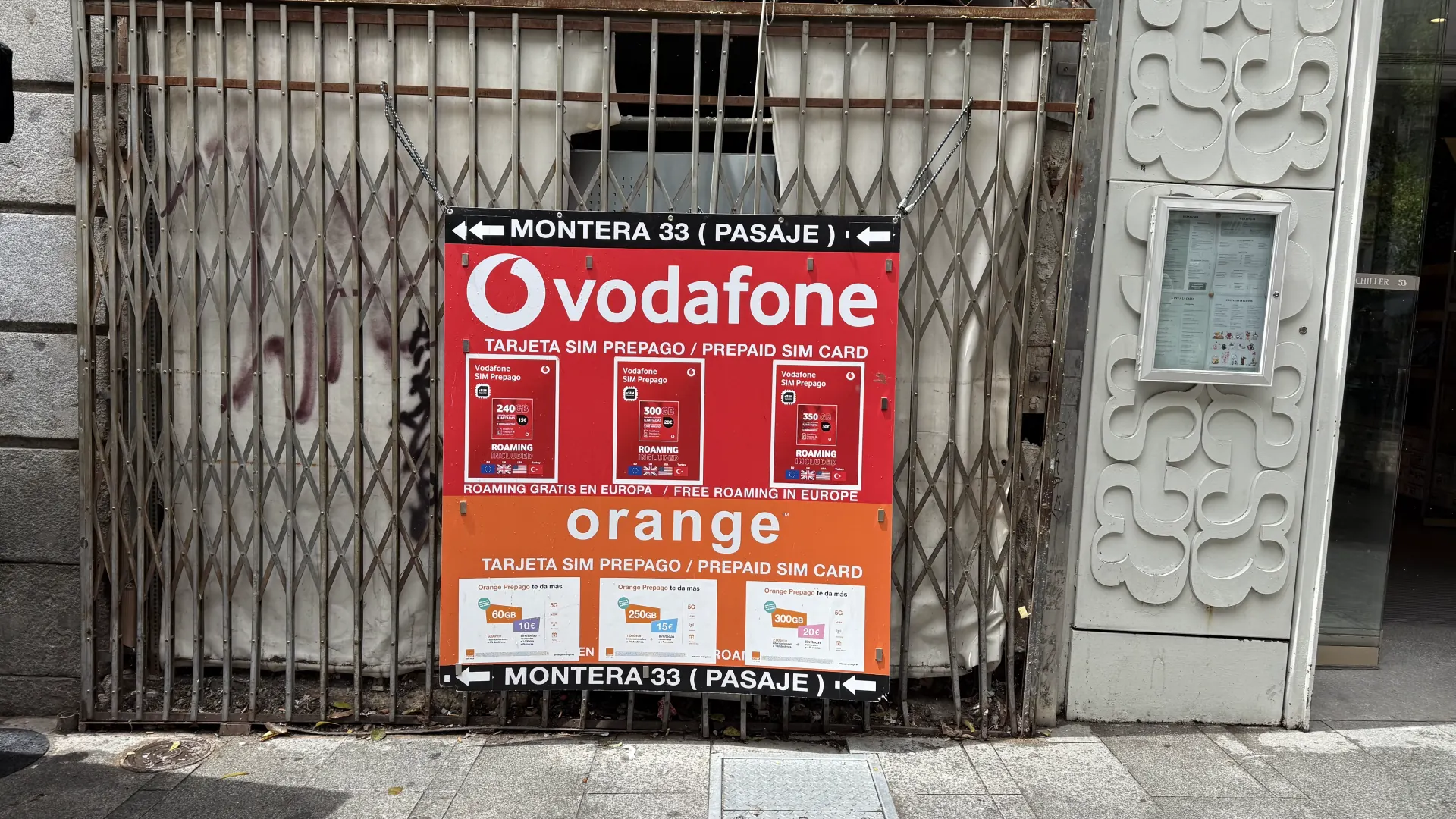 Street sign in central Madrid advertising Vodafone and Orange prepaid SIM cards, with bundles such as 240 GB for 15 euros and 300 GB for 20 euros, and free roaming in Europe