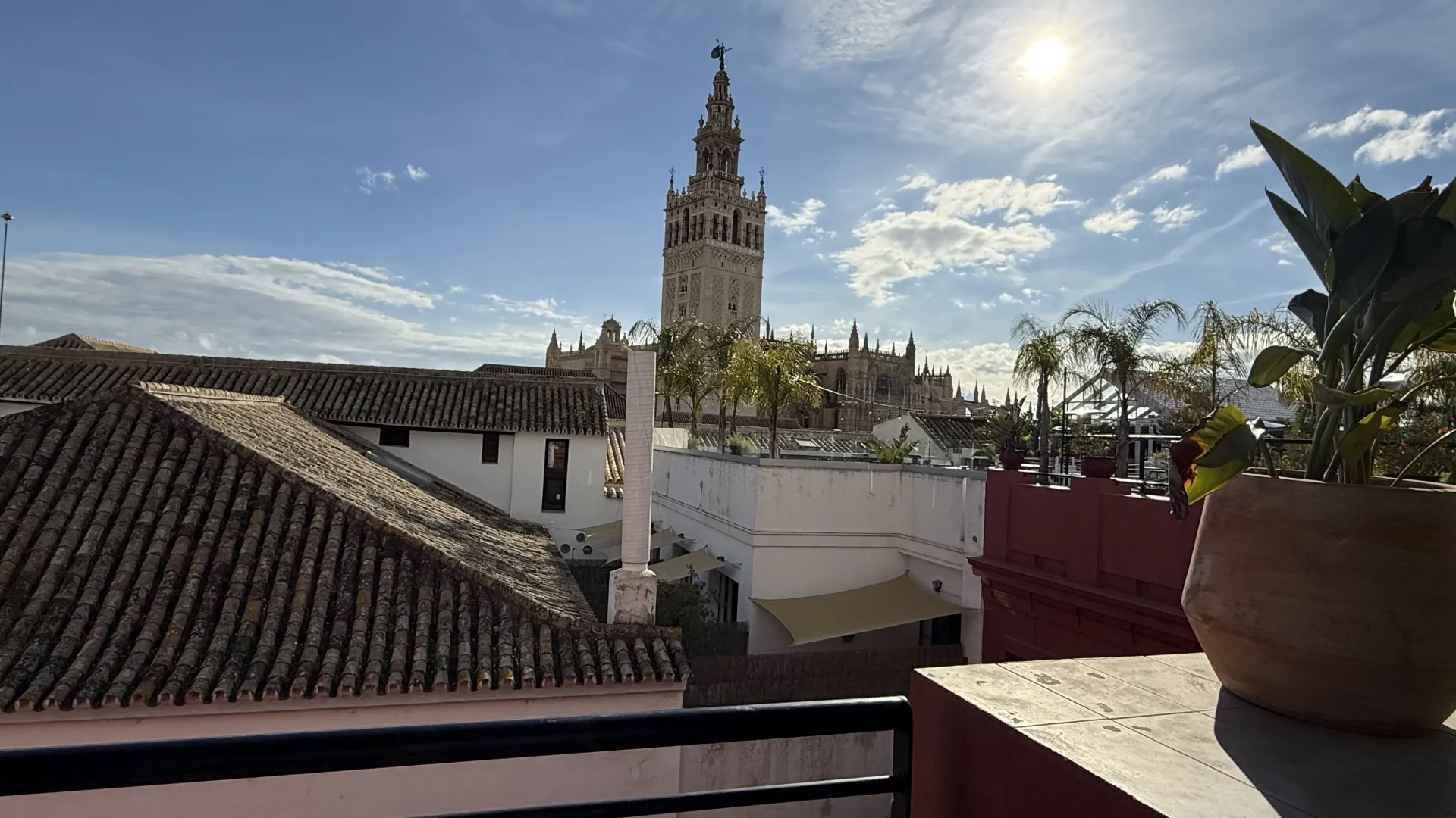 View over tiled rooftops towards the Giralda bell tower and Seville cathedral on a sunny afternoon