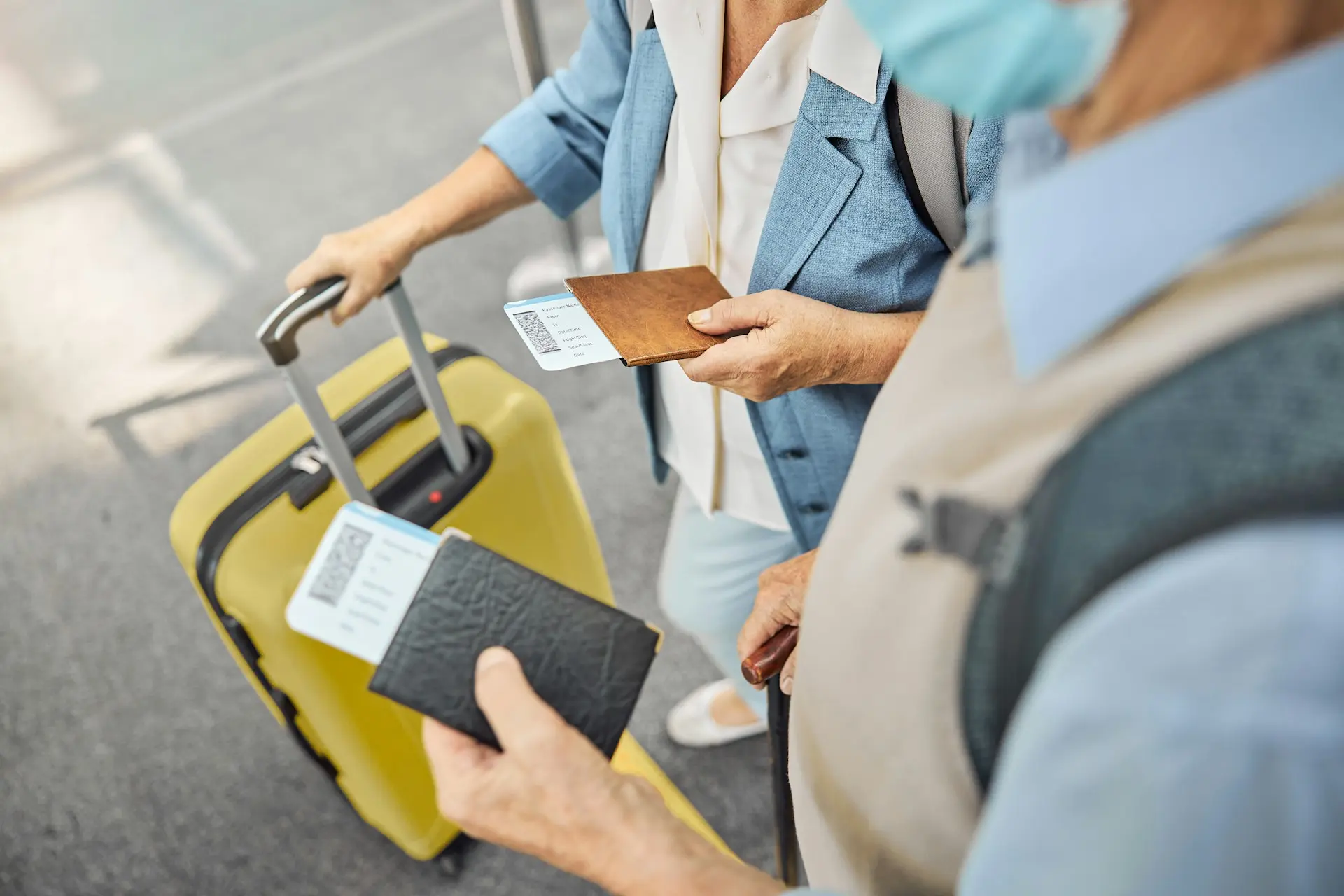 Illustration of two travelers holding their passports and flight tickets, standing near a yellow suitcase at the airport.