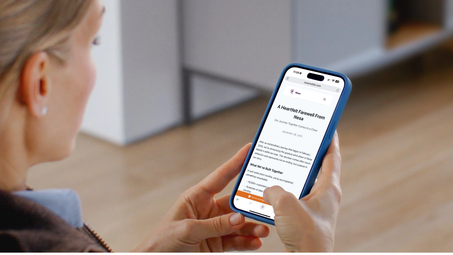 A woman holding a smartphone and reading Nesa Mobile’s farewell announcement titled “A Heartfelt Farewell From Nesa” on the company’s website